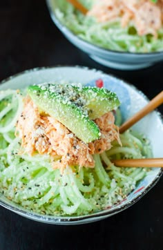 two bowls filled with food and chopsticks on top of a black table next to each other