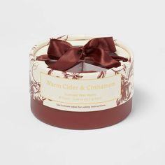 a candle with a brown bow on the top and label that says warm cider & cinnamon