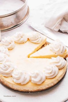 a cheesecake with white frosting on a plate next to a glass cake pan