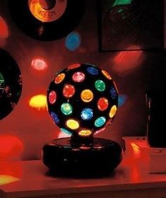 an illuminated disco ball sits on top of a table in front of several framed pictures