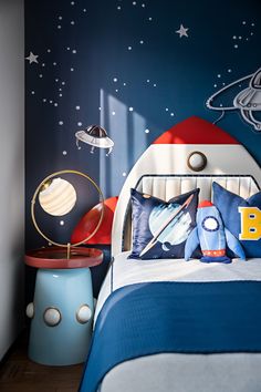 a child's bedroom with blue walls and outer space themed decor on the bed