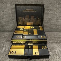 three black and gold boxes with numbers on them sitting on a gray couch in front of a cityscape