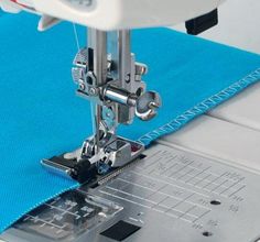 the sewing machine is on top of the blue cloth that's being sewn