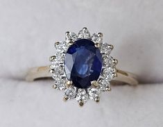 an oval shaped blue sapphire surrounded by small white diamond halos on a gold band