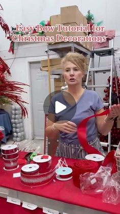 a woman standing in front of a red table with christmas decorations and presents on it