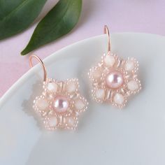 Our pink pearl flower earrings feature a beautiful crystal pearl, surrounded by pink seed beads that are hand woven into a floral pattern.  The beaded flowers dangle from handmade rose gold earrings creating a harmonious and eye-catching design. The coquette jewelry is ideal for spring and summer wardrobes adding a touch of glamour and femineity to your everyday look. The nature inspired earrings are lightweight and comfortable to wear, making them a great choice for all-day wear.    FIT:  The p Elegant Pink Flower Beaded Earrings, Pink Pearl Beaded Earrings, Elegant Pink Round Bead Flower Earrings, Elegant Pink Round Beaded Flower Earrings, Embroidery Jewellery, Earrings For Spring, Coquette Jewelry, Pearl Flower Earrings, Pink Pearl Earrings