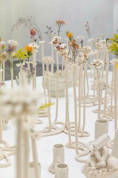 a bunch of white vases with flowers in them sitting on top of a table