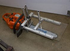 an orange and white machine sitting on the ground next to a wall with tools in it