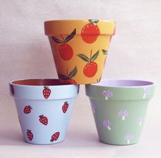 three pots with different designs on them, one has strawberries and the other has mushrooms