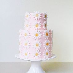 a pink and white cake with daisies on it