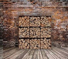 a stack of firewood sitting on top of a wooden floor next to a brick wall