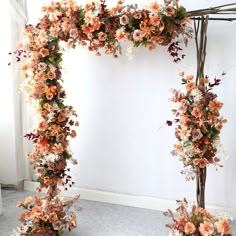 an arch made out of branches with flowers and leaves on the top, along with two vases