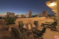 a table and chairs on top of a roof with city lights in the background at night