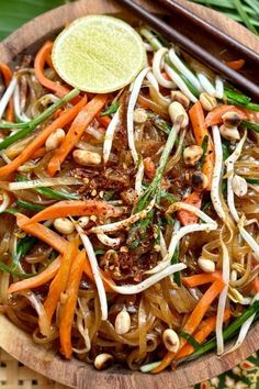 a wooden bowl filled with noodles and vegetables