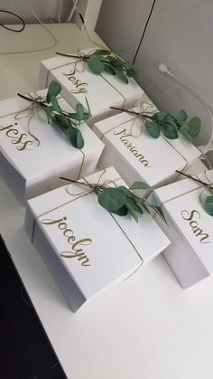 four white boxes with greenery tied to them sitting on a table next to a computer