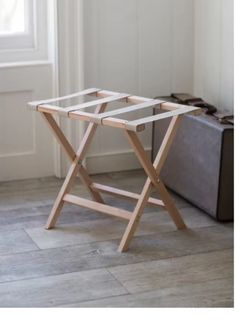 a small wooden table sitting on top of a hard wood floor next to a suitcase