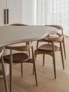 an oval table with four chairs around it in a white walled dining room, next to a sliding glass door