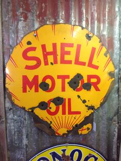 an old shell motor oil sign on the side of a metal wall next to another one