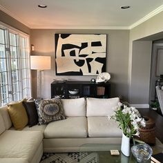 a living room filled with furniture and a large painting on the wall above it's windows