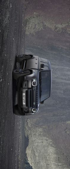 an overhead view of a black car parked on the side of a road with mountains in the background