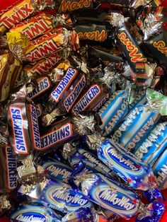 a red bowl filled with lots of different types of candy bar wrappers and candies