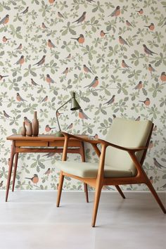 a chair and table in front of a wall with birds on it