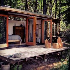 a small cabin in the woods with its doors open and furniture on the ground outside