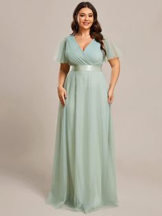 a woman in a green dress posing for the camera with her hands on her hips