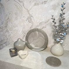 vases, plates and other decorative items are sitting on a countertop in front of a wallpapered background