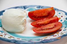 a plate topped with sliced tomatoes next to a scoop of ice cream on top of it