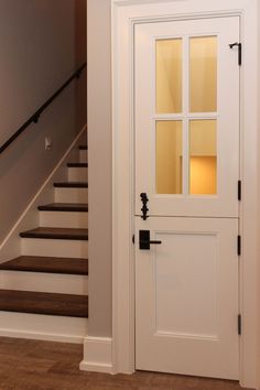 a white door with glass on the side and stairs in the backround behind it