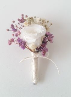 a boutonniere with white and purple flowers is tied to the wall by a string