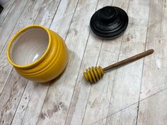 a wooden table topped with a yellow vase and a honey dipper