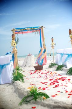 an outdoor ceremony setup on the beach with blue and white linens, flowers and decorations