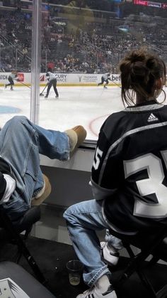 two people sitting on the bench watching an ice hockey game