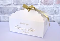 a white gift box with a gold ribbon on it and a thank you tag attached to the top