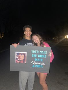 two people standing next to each other holding a sign