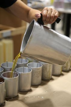 a person pouring something into cups on a table