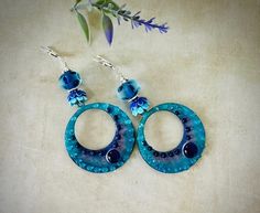 "These big colorful hoop earrings are comprised of enameled hoop charms 38mm across by 43mm in length.  These amazing hoops are done in dark and light blue colors with light blue and dark blue\" bubbles\" by glass artist Carolyn. These colorful hoops dangle below 11mm artisan Lampwork glass beads done in a light transparent blue with etched circles. The earrings are accented with ceramic light and dark blue bead caps, Hill Tribe Silver beads and suspend from sterling silver lever back ear wires. The total length is 3 1/4\". These are beautiful, eye-catching earrings! Make a wonderful gift too! Comes in a pretty gift box with fast shipping." Blue Hypoallergenic Small Hoop Earrings, Handmade Blue Round Hoop Earrings, Blue Hoop Earrings With Ear Wire, Blue Hypoallergenic Hoop Earrings, Blue Bohemian Hoop Earrings For Party, Bohemian Blue Hoop Earrings For Party, Blue Small Hoop Nickel-free Earrings, Blue Nickel-free Small Hoop Earrings, Handmade Small Hoop Blue Earrings