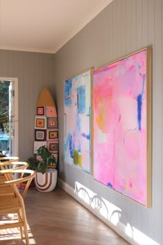 two paintings are hanging on the wall next to a table and chairs in a dining room