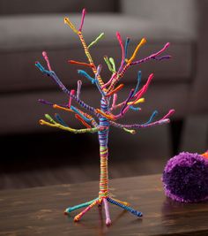 a colorful tree made out of yarn sitting on top of a wooden table