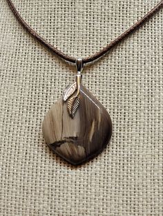 This petrified wood exhibits beautiful shaded grainlines in an onion shaped cabochon pendant. The cut across the growth patterns creates a striking pattern showcasing beiges and brown to form a stunning understated piece. A classic, lightweight pendant that will be a joy to wear. It is held by a simple, two-leaf .925 hypoallergenic sterling silver bail. Definitely a one of a kind pendant that is classic neutral to wear with everything.  Petrified wood that exhibits this nice a pattern is hard to find. An artisan created masterpiece highlighting the stones natural beauty.  Hand crafted into a one of a kind artisan pendant for your comfortable wearing pleasure. See more fine jewelry at https://stonesofold.etsy.com Item Number:  FOC3005 Artisan Brown Jewelry With Natural Inclusions, Brown Pendant Jewelry With Natural Inclusions, Brown Teardrop Agate Jewelry, Nature-inspired Brown Round Pendant Jewelry, Brown Carved Agate Jewelry, Brown Carved Nature-inspired Jewelry, Earthy Brown Teardrop Jewelry, Nature-inspired Brown Carved Jewelry, Unique Brown Jewelry With Natural Variations