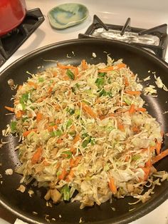 a pan filled with shredded carrots and cabbage on top of a stove burner