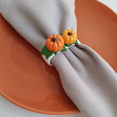 an orange plate topped with a napkin and two small pumpkins