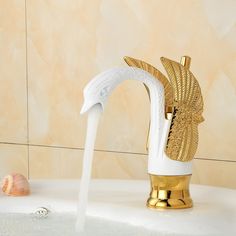 the faucet is pouring water into the bathtub with gold and white fixtures