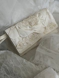 a white purse sitting on top of a bed covered in lace and satin materials