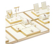 an assortment of jewelry on display with gold and white boxes in the foreground,