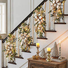 christmas decorations on the banisters and stairs with lit candles in front of them