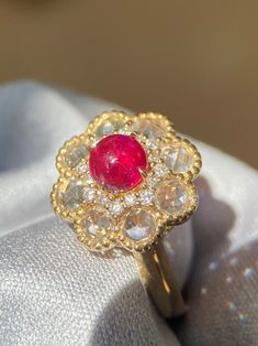 a close up of a ring with a red stone in it on a white cloth