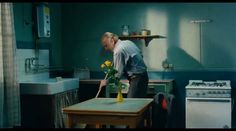 a man standing over a wooden table in a kitchen next to a stove top oven